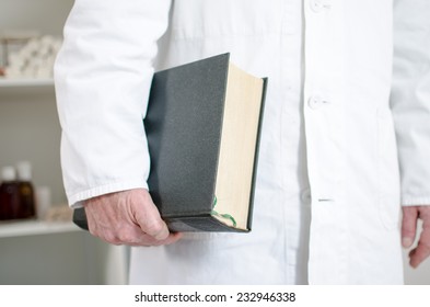 Doctor Holding A Medical Book Under His Arm In His Office