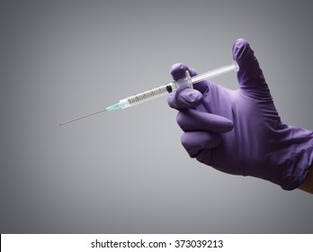 Doctor holding medical injection syringe wearing surgical rubber gloves - Shutterstock ID 373039213