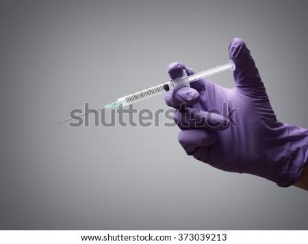 Doctor holding medical injection syringe wearing surgical rubber gloves