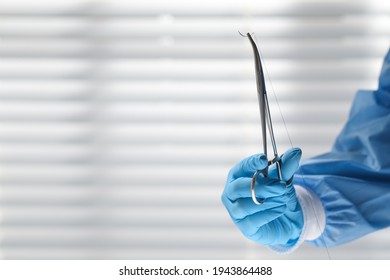 Doctor Holding Needle With Suture Thread Indoors, Closeup And Space For Text. Medical Equipment