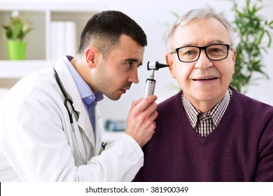 Doctor holding otoscope and examining senior patient ear - Powered by Shutterstock