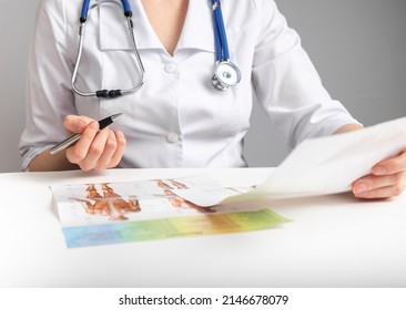 Doctor holding papers and studying anatomy. Medicine education and research conducting concept. Woman in lab coat with stethoscope sitting at table and analyzing documents. High quality photo - Shutterstock ID 2146678079