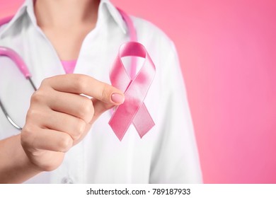 Doctor holding pink ribbon on color background. Breast cancer awareness concept - Shutterstock ID 789187933