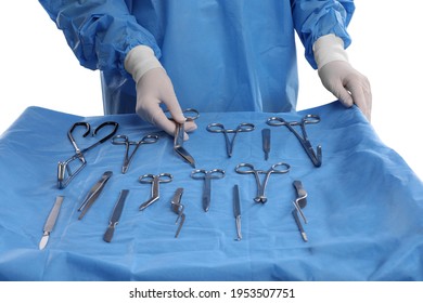 Doctor Holding Pott's Scissors Near Table With Different Surgical Instruments On Light Background, Closeup