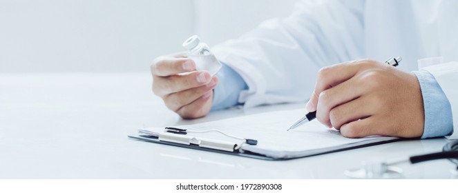 Doctor Holding Prescription Bottle And Writing Prescription On Special Form At Office Room. Healthcare, Vaccine,medical And Pharmacy Concept.