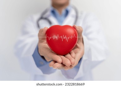 Doctor holding red heart shape in hand and modern medical network icon connected to virtual screen medical technology network concept. Medical and patient.