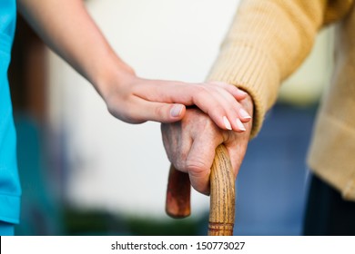Doctor holding a senior patients 's hand on a walking stick - special medical care concept for Alzheimer 's syndrome.