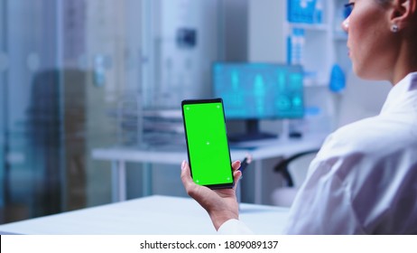 Doctor Holding Smartphone With Copy Space Available In Clinic Cabinet And Nurse Opening Glass Door. Healthcare Specialist In Hospital Cabinet Using Smartphone With Mockup.