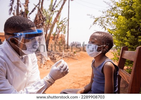 A doctor holding a swab to perform a molecular test on a child in Africa.