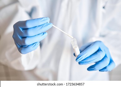 Doctor holding swab test tube for 2019-nCoV analyzing. Coronavirus test. Blue medical gloves and protective face mask for protection against covid-19 virus. Coronavirus and pandemic. - Shutterstock ID 1723634857
