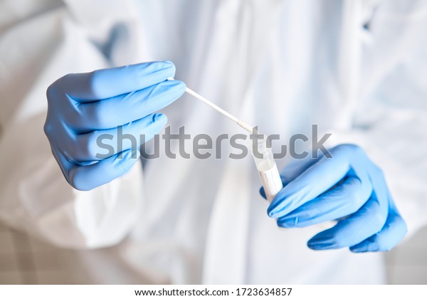 Doctor holding\
swab test tube for 2019-nCoV analyzing. Coronavirus test. Blue\
medical gloves and protective face mask for protection against\
covid-19 virus. Coronavirus and\
pandemic.