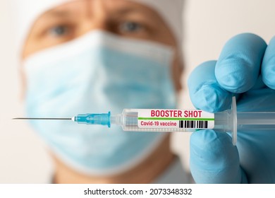 Doctor holding syringe with Covid-19 vaccine with inscription booster shot. Concept of third booster dose of vaccine - Shutterstock ID 2073348332