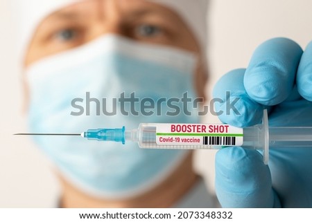 Doctor holding syringe with Covid-19 vaccine with inscription booster shot. Concept of third booster dose of vaccine
