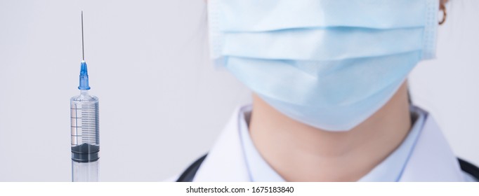 Doctor holding syringe with face mask, concept of young female physican injects coronavirus, COVID-19 vaccine on white background, close up, copy space