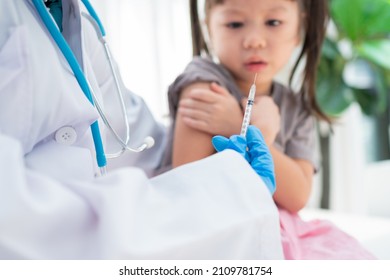 Doctor holding syringe for prepare vaccinated in the shoulder of Asian girl kids in the hospital. Pediatrician makes vaccination for kids. Vaccination, immunization, disease prevention concept.