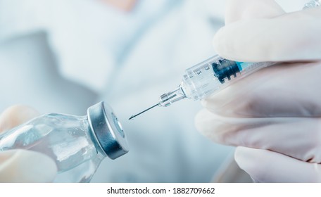 Doctor holding a syringe with a single bottle vial of Covid-19 vaccine for children or adults. Concept fight against virus. Close up detail. Medical concept vaccination hypodermic injection treatment. - Powered by Shutterstock