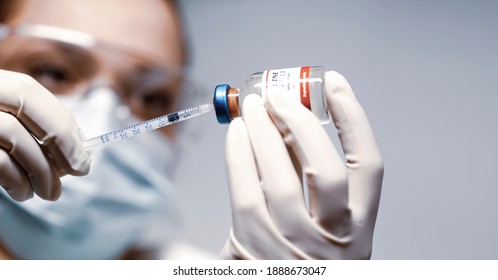 Doctor holding a syringe with a single bottle vial of Covid-19 vaccine and she is ready for vaccination. Close up. Medical concept vaccination hypodermic injection treatment.  Copy space for text.