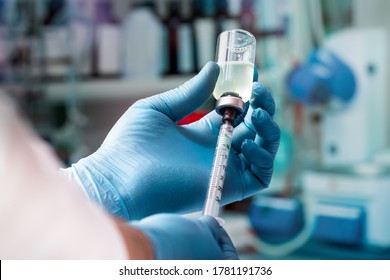 Doctor holding a syringe and a vaccine / hands of a doctor preparing a dose for the vaccination campaign