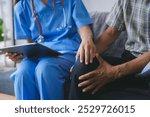 Doctor holding a tablet is comforting an elderly patient suffering from knee pain