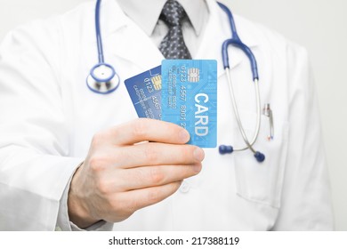 Doctor Holding Two Credit Cards In His Hand - Closeup Studio Shot