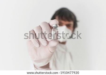 Doctor holding a vaccine bottle and syringe, beginning of worldwide mass vaccination for coronavirus COVID-19, influenza or flu, world immunization concept. Selective focus