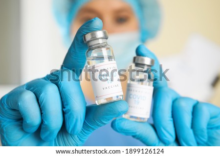 Doctor holding vials with vaccine against Covid-19 indoors, closeup