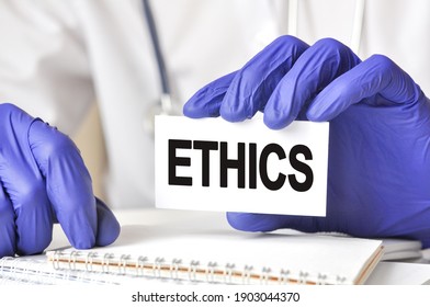 Doctor Holding A White Paper Card With Text: Ethics. Healthcare Conceptual For Hospital, Clinic And Medical Business.