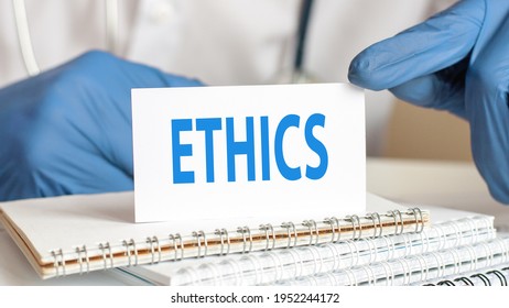 Doctor Holding A White Paper Card With Text: ETHICS. Healthcare Conceptual For Hospital, Clinic And Medical Busines.