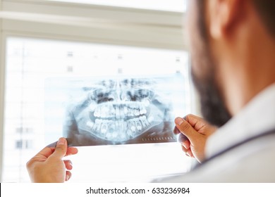 Doctor Holding X-ray Image From Jaw And Making Diagnostic For Oral Surgery