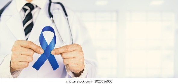 Doctor Holds Blue Ribbon,  Colon Cencer Awareness. Symbolic Concept Raising Awareness Concerns Help Campaign On People Living Colorectal Cancer Illness.