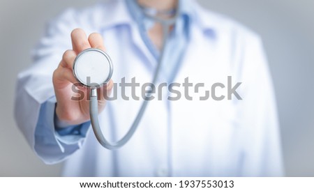 Doctor holds his stethoscope to insinuate that it's time for a check up, professional emergency healthcare assistance service concept                                                                  