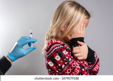 Doctor Holds An Injection Vaccination The Child. Doctor Holding A Syringe With Injection Vaccination. Girl Is Afraid.
