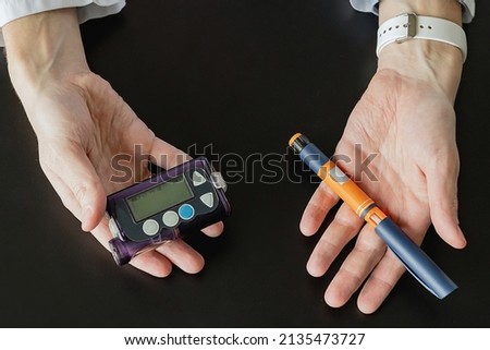the doctor holds an insulin syringe and an insulin pump in his hands. Diabetes is a disease of the endocrine system. Syringe on a black background. Diabetes treatment choice concept