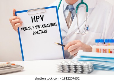 Doctor Holds Paper With Inscription HPV - Human Papillomavirus Infection, Stethoscope And Pills On Table