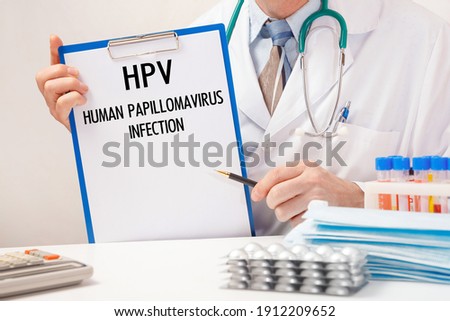 Doctor holds paper with inscription HPV - Human papillomavirus infection, stethoscope and pills on table