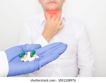 The Doctor Holds Pills In His Hand Against The Background Of A Man With A Diseased Thyroid Gland. Thyroid Medication Concept, Hormone Therapy, Iodine Therapy, Endocrinology