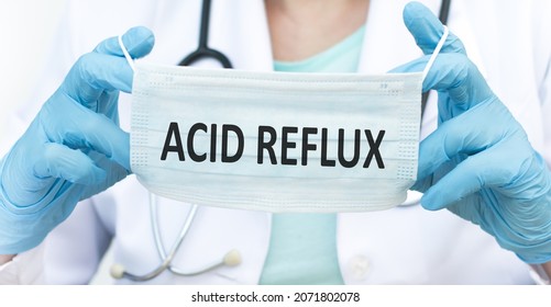 Doctor Holds A Protective Blue Mask With The Text Acid Reflux. Medical Concept.