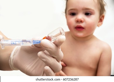 Doctor holds syringe to vaccinate baby with injection