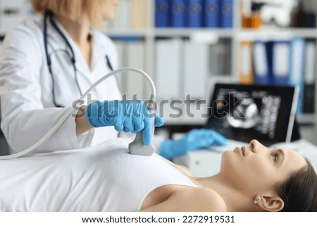 Doctor holds ultrasound probe on chest of patient in clinic closeup