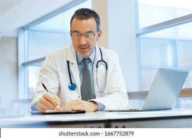 Doctor In Hospital Office Working On Laptop