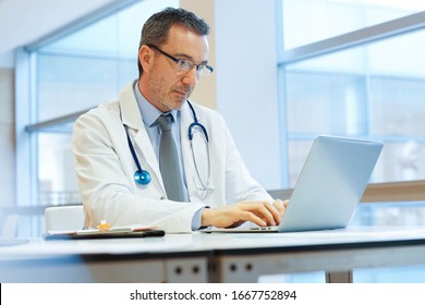 Doctor In Hospital Office Working On Laptop