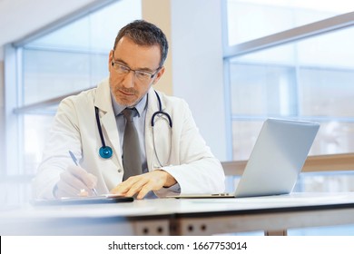 Doctor In Hospital Office Working On Laptop