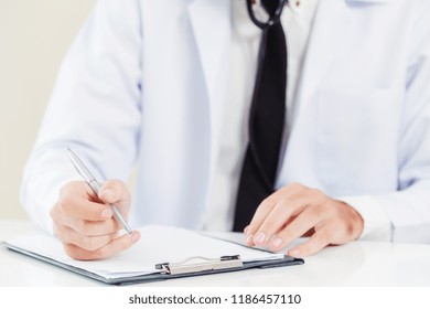 Doctor In Hospital Working And Writing On Paperwork. Healthcare And Medical Service Concept.