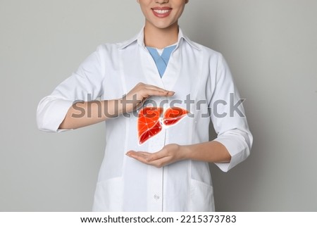 Doctor and illustration of healthy liver on beige background, closeup