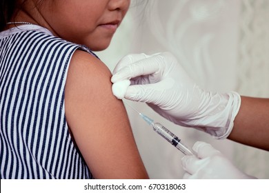 Doctor injecting vaccination in arm of asian little child girl,healthy and medical concept - Shutterstock ID 670318063
