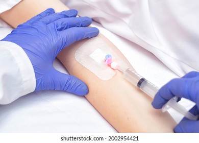 The doctor injects the medicine from a syringe into the female patient's venous catheter. Pain reliever and anti-inflammatory agent, vasodilator. Intravenous