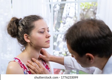 Doctor inspecting, doing palpation examination of young woman with Grave's disease hyperthyroidism symptoms of enlarged thyroid gland goiter and ophthalmopathy in hospital