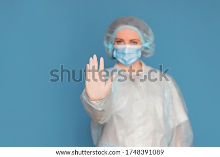 Doctor in a lab coat, mask. A surgeon with clinical experience in healthcare, patient care. Stop coronavirus. Copy space, isolated blue background.