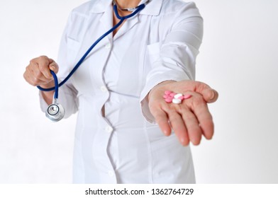 doctor in a lab coat and with a stethoscope holding a pill            - Shutterstock ID 1362764729