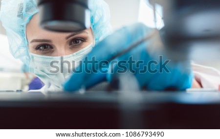 Doctor or lab technician adjusting needle to fertilize a human egg under the microscope